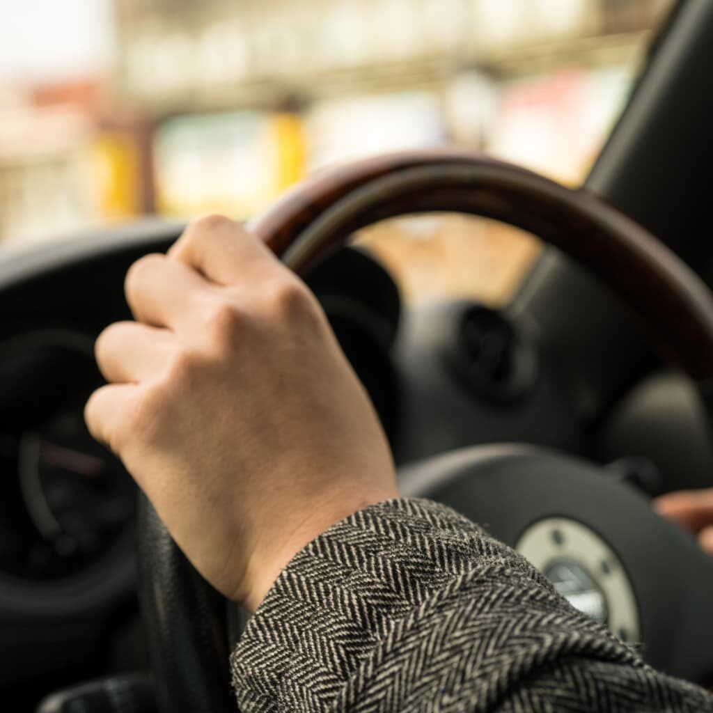 Person holding a car steering wheel